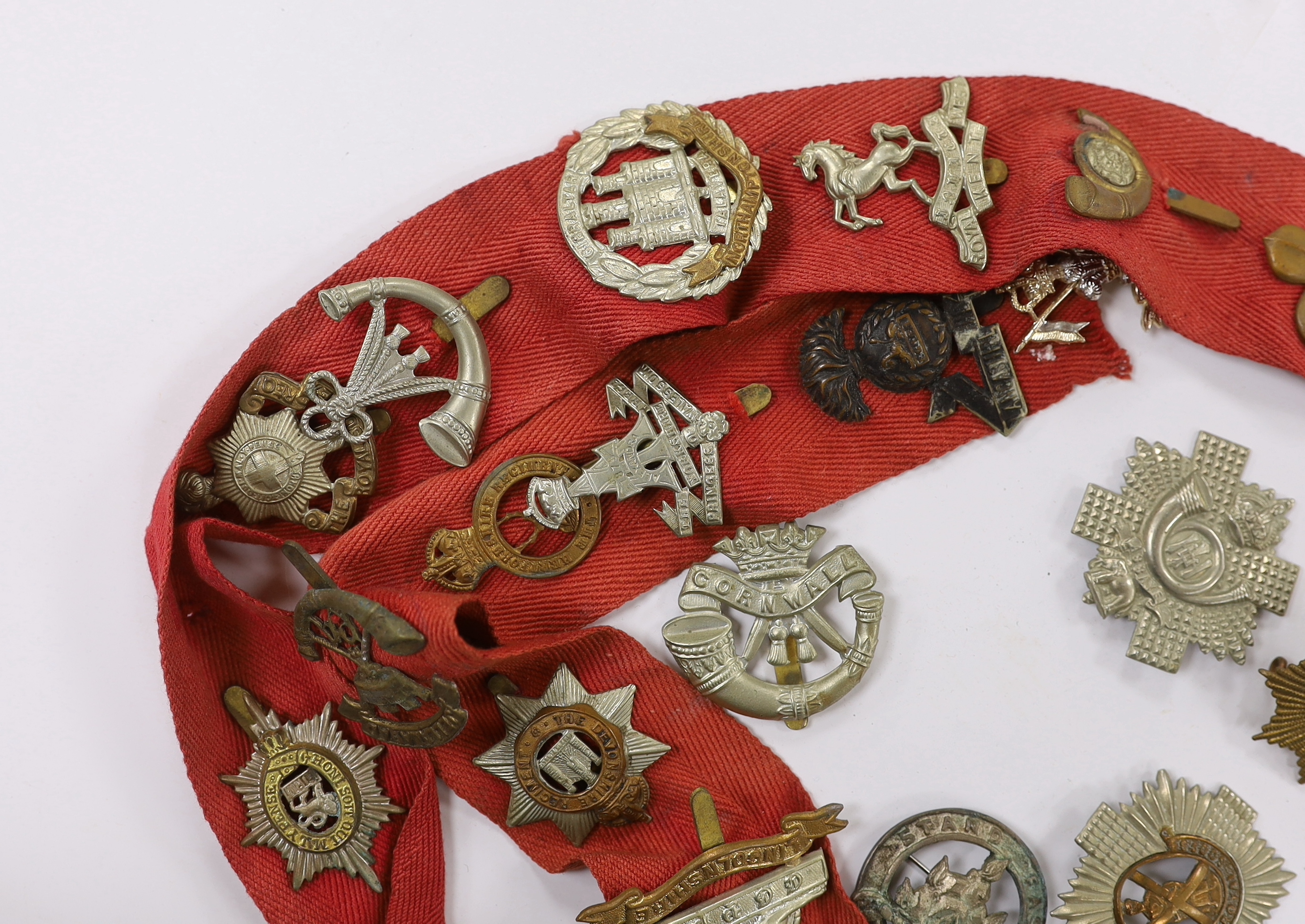 Thirty-two military cap badges, including; The Devonshire Reg., The Buffs, RFC, Royal Artillery, The Royal Sussex Reg. Royal Warwickshire Reg., Cornwall, etc.